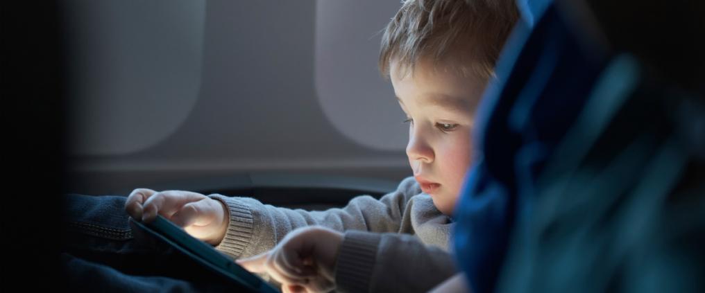 Toddler is using a tablet on flight.