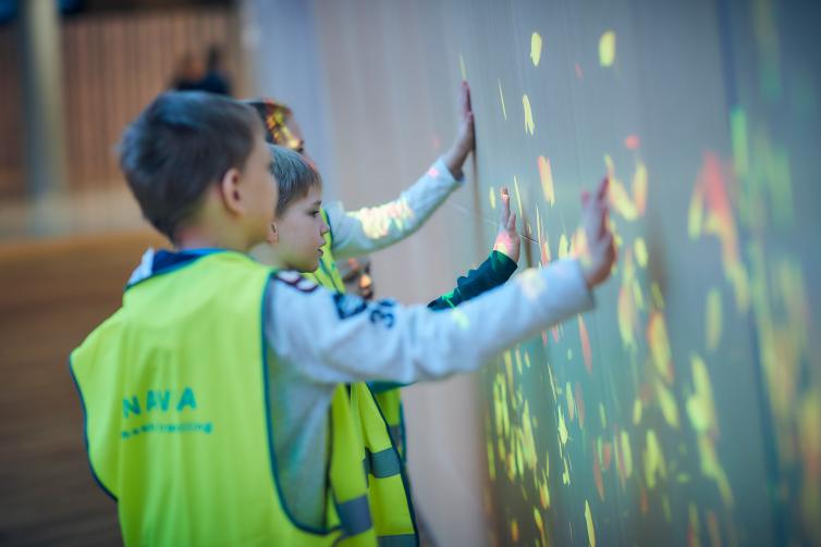Lapset leikkivät seinään heijastetulla interaktiivisella valoheijastuksella.