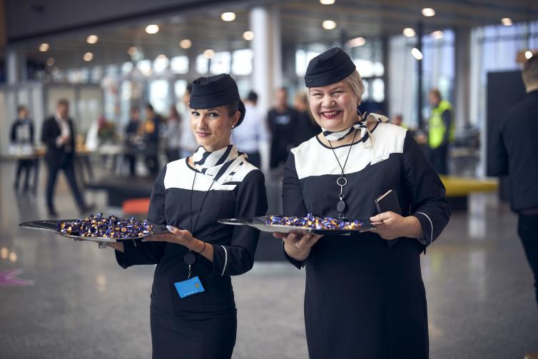 Hymyilevät Finnairin virkailijat suklaatarjottimien kanssa.