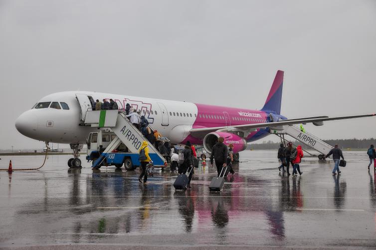 Passengers boarding Wizz Air's airplane in the rain.