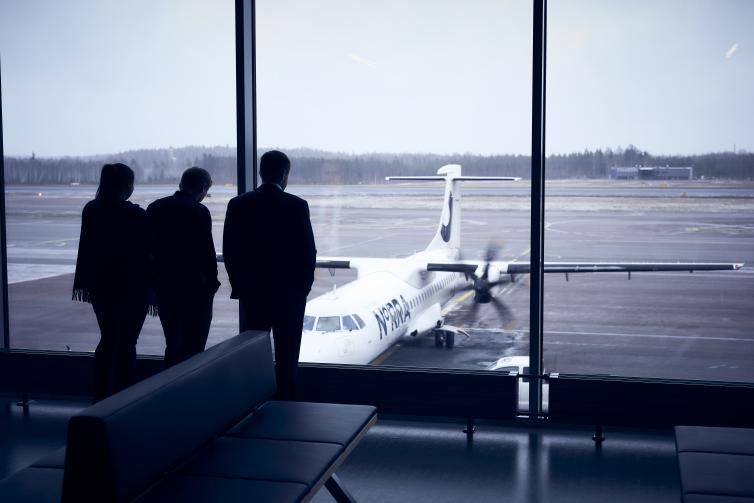 Three men looking at an airplane through a window.