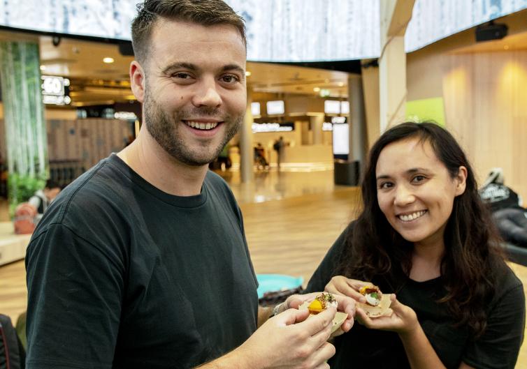 Hymyilevä pariskunta herkkujen kanssa the Happy Food Market -tapahtumassa.