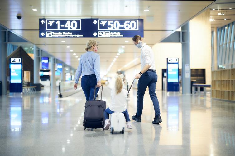 Perhe kävelee Helsinki-Vantaan lentoasemalla.