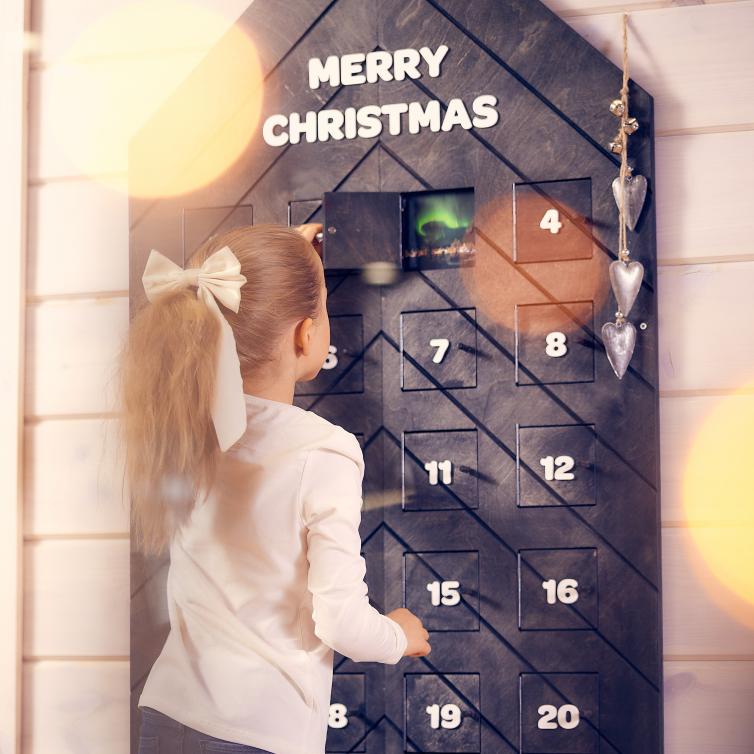 Tyttö kurkistaa joulukalenterin luukkuihin. 