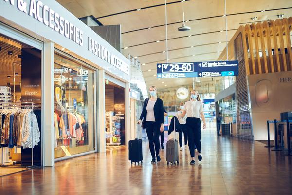 Matkustajat kulkevat lentoasemalla maskit päässään. 