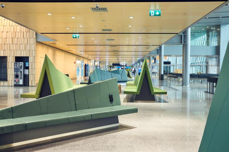 Vihreitä metsäteemaisia sohvia lentoaseman leveällä käytävällä