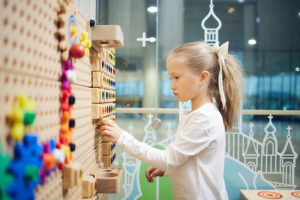 Lapsi leikki värikkäillä palikoilla, jotka on kiinnitetty seinään.