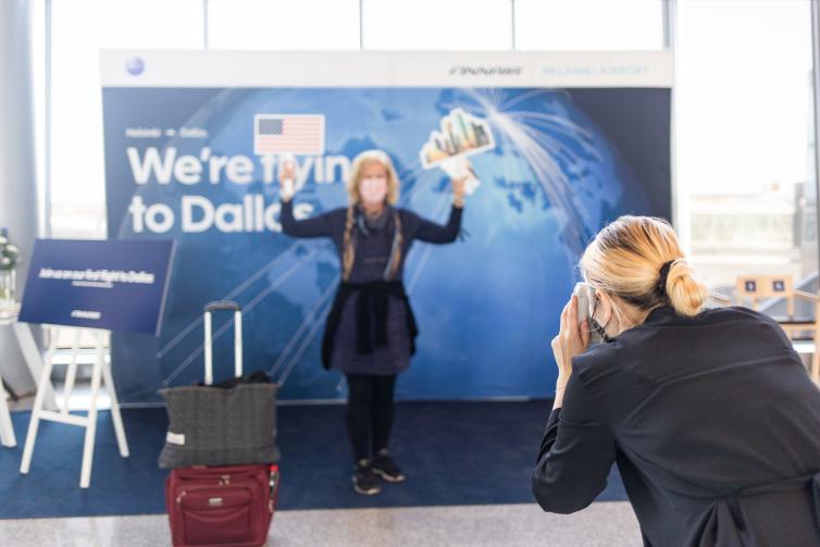Matkustaja kuvauttaa itsensä Finnairin Dallasin reittiavauksen kuvausseinällä