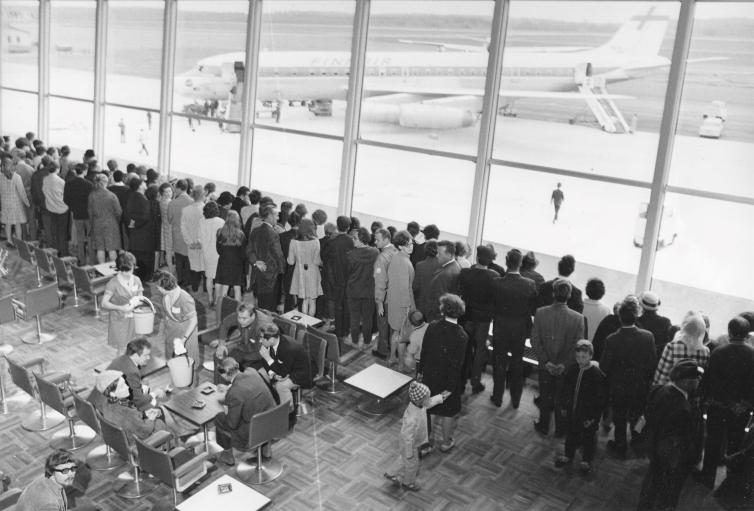 Matkustajia seuraamassa lentokoneen kääntöä vuonna 1969 valmistuneessa terminaalissa.