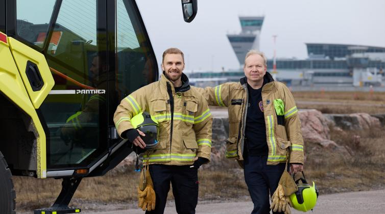 Kaksi pelastajaa Helsinki-Vantaan lenotasemalla, taustalla lennonjohtotorni