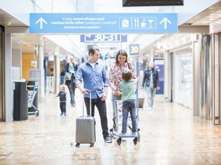 A family at Helsinki Airport's corridor going to the gate.