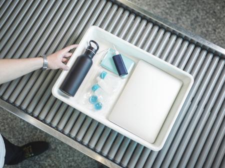 Liquid products and electronics on a security control tray.