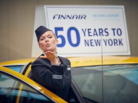 Keltaisesta taksista nouseva purseri puhaltaa lentosuukkoa.