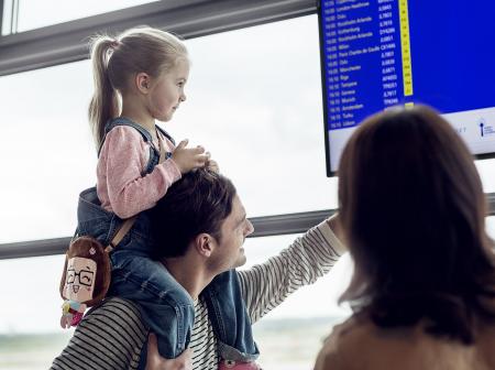 Perhe tarkastelee lähtoaikatauluista kertovaa näyttöä.