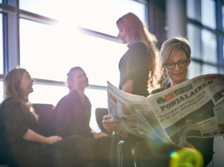 Matkustaja lukee lehteä Vaasan lentoasemalla. 