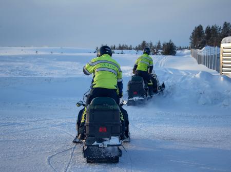 Two airport staff members riding snowmobiles.