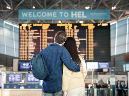 A couple in front of the big screen at Helsinki Airport