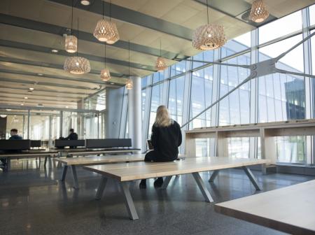 Yksittäinen matkustaja istuu penkillä valoisassa terminaalissa