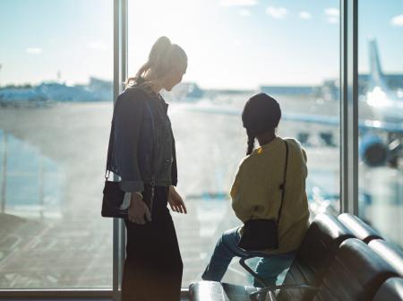 Kaksi henkilöä katsoo ikkunasta ulos lentoasemalla.