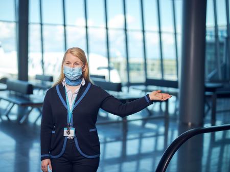 Finavian henkilökunta ohjeistaa matkustajia kädellä maski naamassa