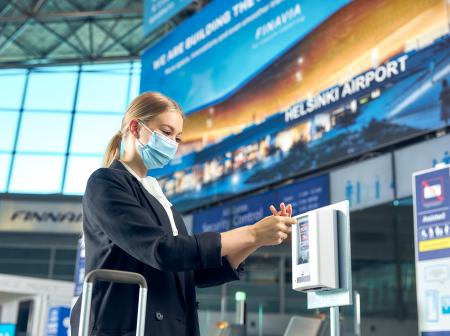 Matkustaja desinfioi käsiään maski naamalla