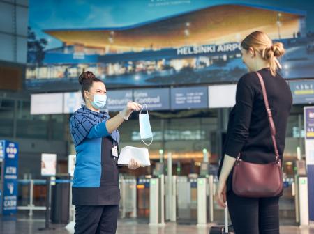 A passenger service person gives a mask for a passengers