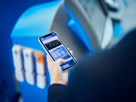 Matkustaja tutkii tietoja kännykästään Helsinki-Vantaan lentoasemalla. 