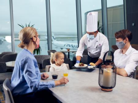 Perhe ruokailee Helsinki-Vantaan lentoasemalla.