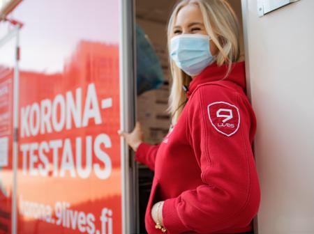 Punapukuinen 9Livesin työntekijä koronatestauspisteen ovella