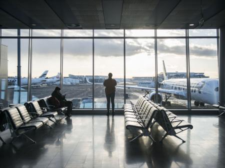 Iso lasiseinä, jonka edessä seisoo ihminen. Takana näkyy lentokoneita.