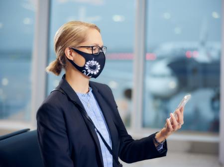 Matkustaja istuu porttialueella ja katsoo puhelintaan.