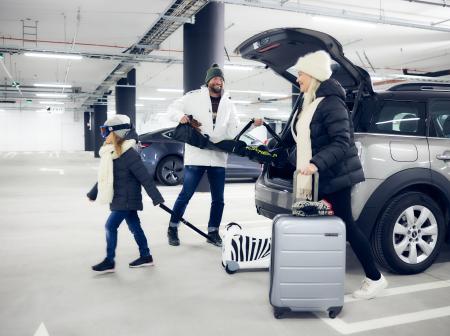 Perhe purkamassa autosta parkkihallissa talvivarusteita.