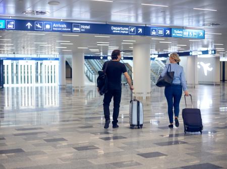Kaksi ihmistä kävelee poispäin kuvasta lentoaseman aulassa