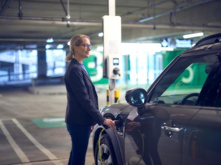 Matkustaja lataa autoaan Helsinki-Vantaan lentoaseman pysäköintihallissa
