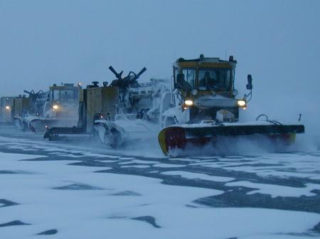 Kunnossapitokalusto auraa lunta iltahämärässä