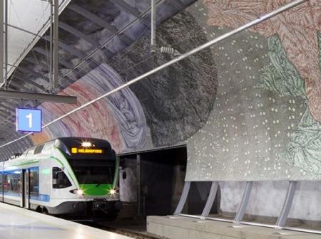 Juna saapuu asemalaiturille, joka on koristeltu isolla taideteoksella