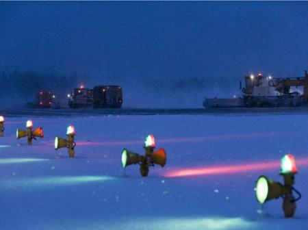 Yöaikaan otettu kuva kiitotievaloista ja kunnossapitokalustosta.