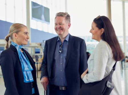 Kolme henkilöä keskustelee lentoaseman lähtöaulassa.