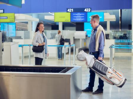 Kuvassa mies seisoo golf-kassin kanssa lähtöselvitystiskin edessä. 