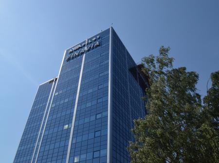Korkea, sinisävyinen, lasiseinäinen toimistorakennus, jonka vieressä koivu ja takana sininen taivas.