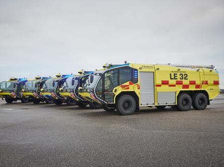 Rivi isoja, keltaisia sammutusautoja lentoasemalla.