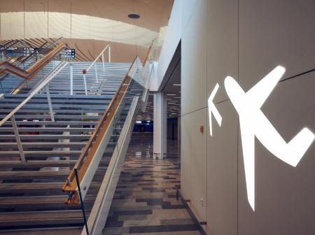 Kuvassa portaat, joissa on puinen kaide ja lentokoneen muotoinen valokyltti.