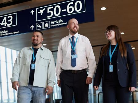 Kolme Finavian työntekijää kävelee kohti kameraa lentoaseman sisätiloissa.