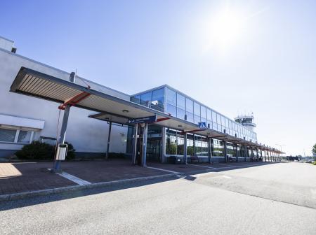 Kuopion lentoaseman pääsisäänkäynti ja edusta kuvattuna aurinkoisena päivänä.