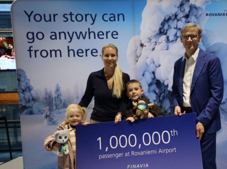 Ryhmäkuva matkustajista ja lentoasemanpäälliköstä ison miljoonas matkustaja -kyltin kanssa.