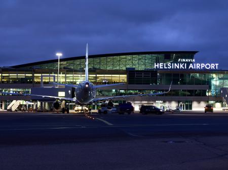 Helsinki-Vantaan lentoaseman terminaali ja asematasolla odottava lentokone kuvattu yöaikaa.