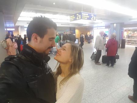 A couple smiling and looking into each others eyes at 2B arrival hall at Helsinki Airport.