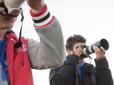 Kaksi nuorta miestä tarkkailee ja valokuvaa lentokoneita.