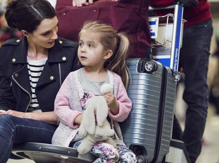 Mother and a small child sitting on a luggage trolley.