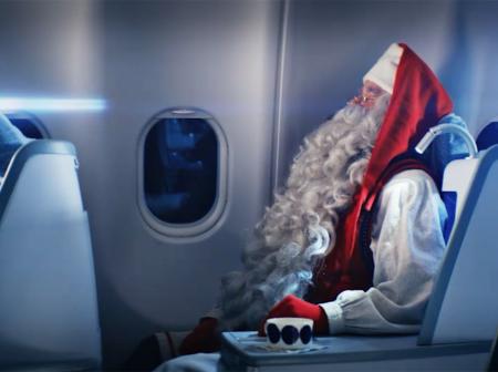 Santa Claus sitting in airplane cabin.
